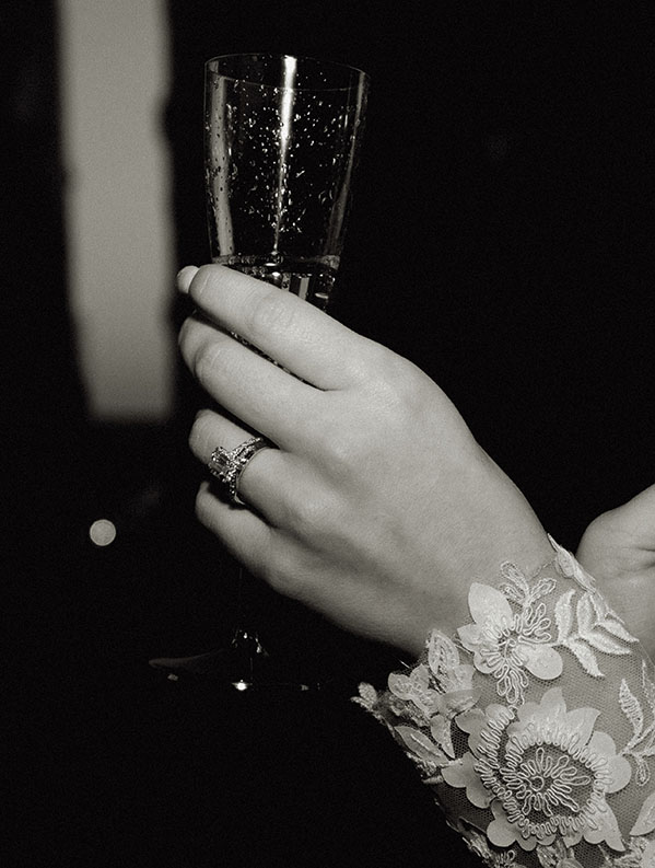Bride's hand holding a champagne glass showing off her engagement ring. 