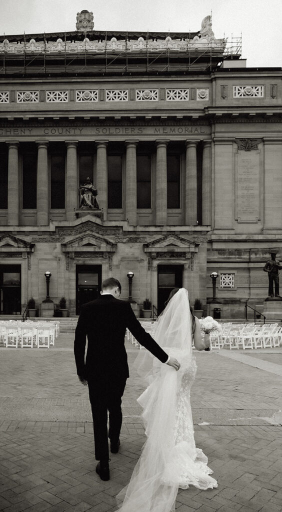 BW Groom helps Bride wedding gown as they walk towards their reception