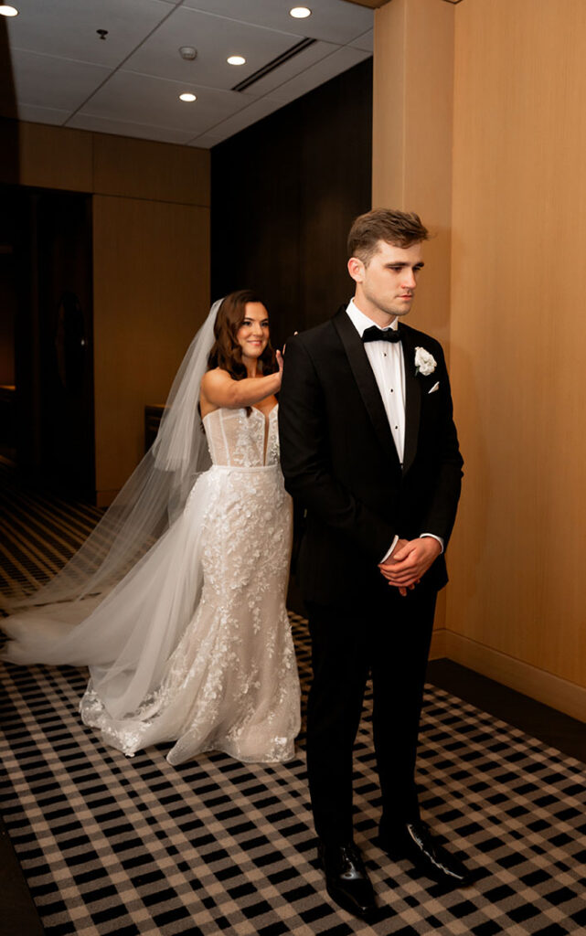 Bride taps groom in the shoulder for their first look at the Oaklander Hotel