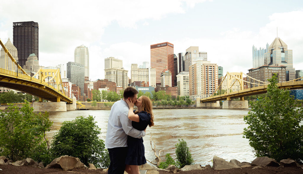 Couple in front of Pittsburgh kissing