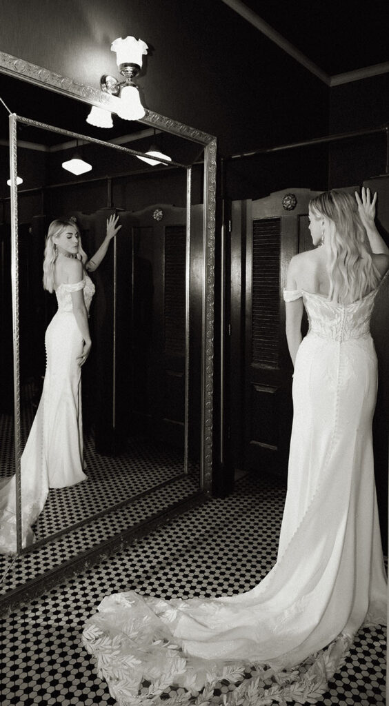 Bride in front of the mirror showing off her wedding gown and figure