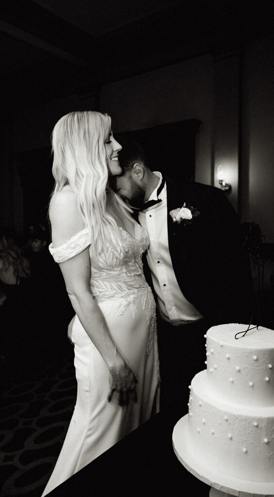 Bride and groom laughing as they're about to cut the cake