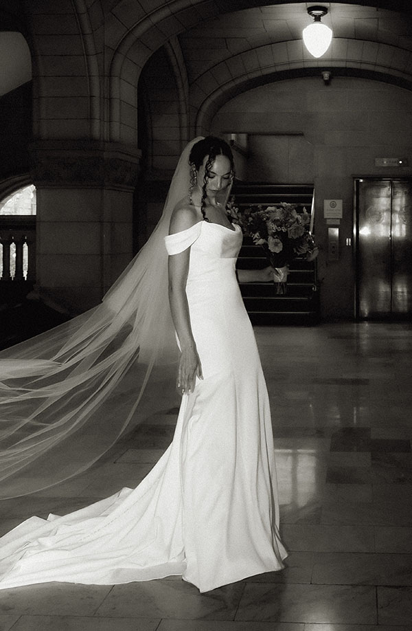Bride wearing a sleek white gown and long veil walking up the courthouse steps in Downtown Pittsburgh during her elopement.