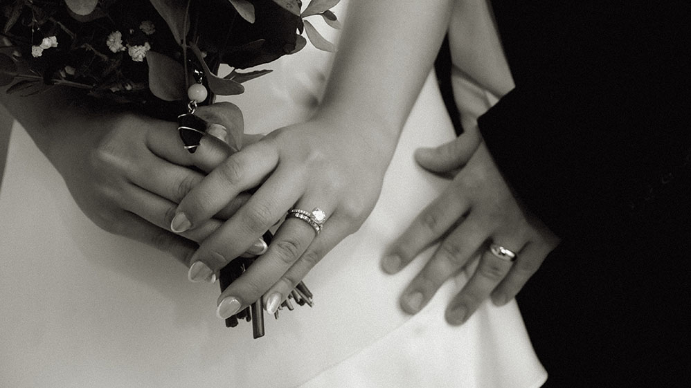 Bride holding bouquet showing off wedding bands