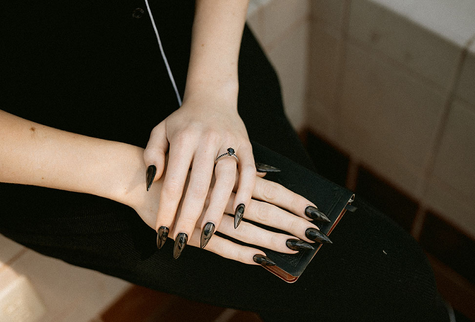 Bride white skin with black long nails holding her vows book