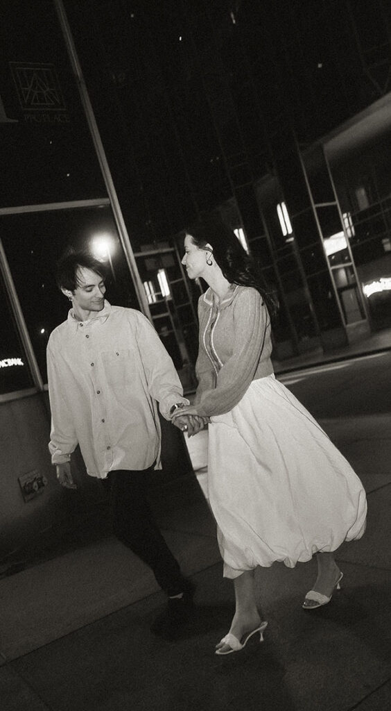 Couple walking hand in hand down Smithfield Street surrounded by nighttime city lights.