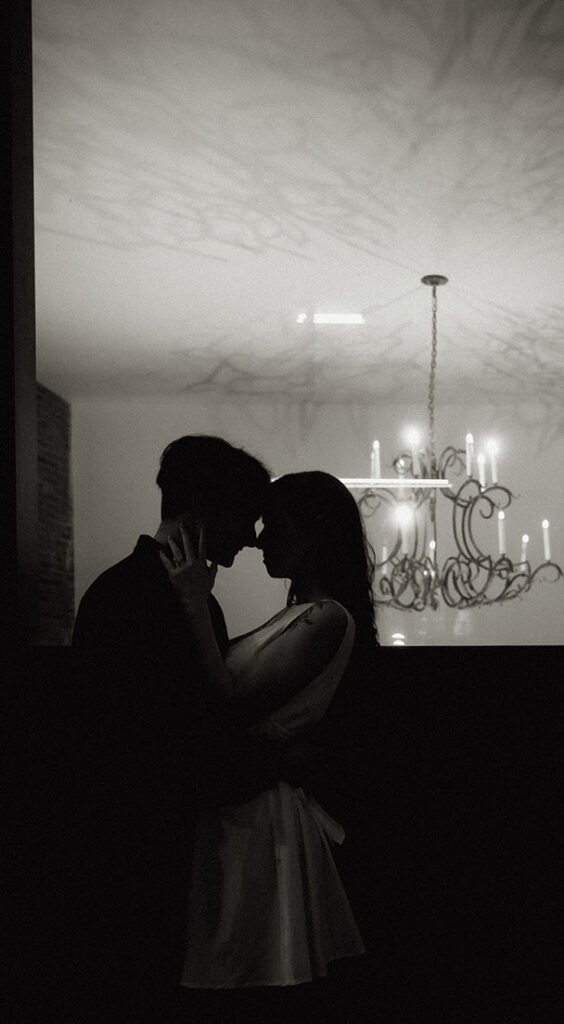 Silhouette of a couple crossing a Pittsburgh street with tall buildings behind them.