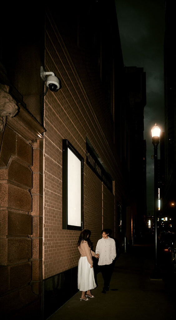 Cinematic street photo of a couple embracing under Pittsburgh street lights.
