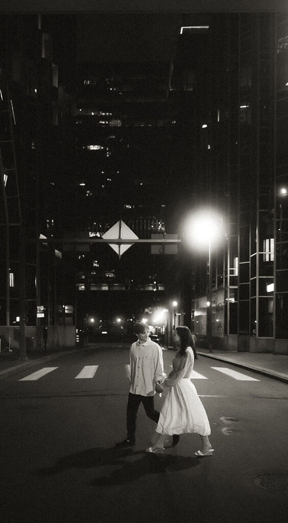 Couple walking through Market Square at night with warm city lights behind them.