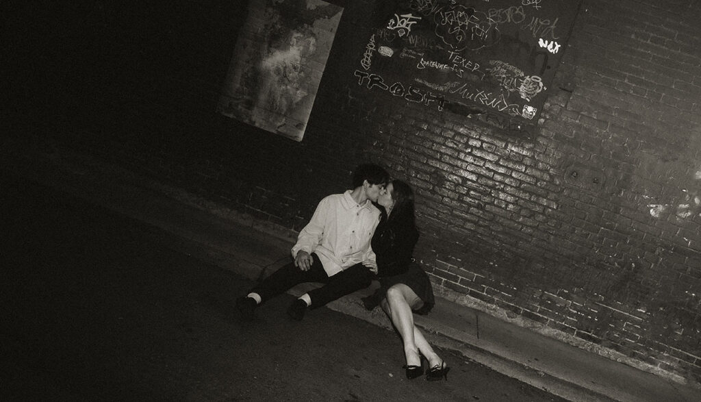 Cinematic street photo of a couple embracing under Pittsburgh street lights.