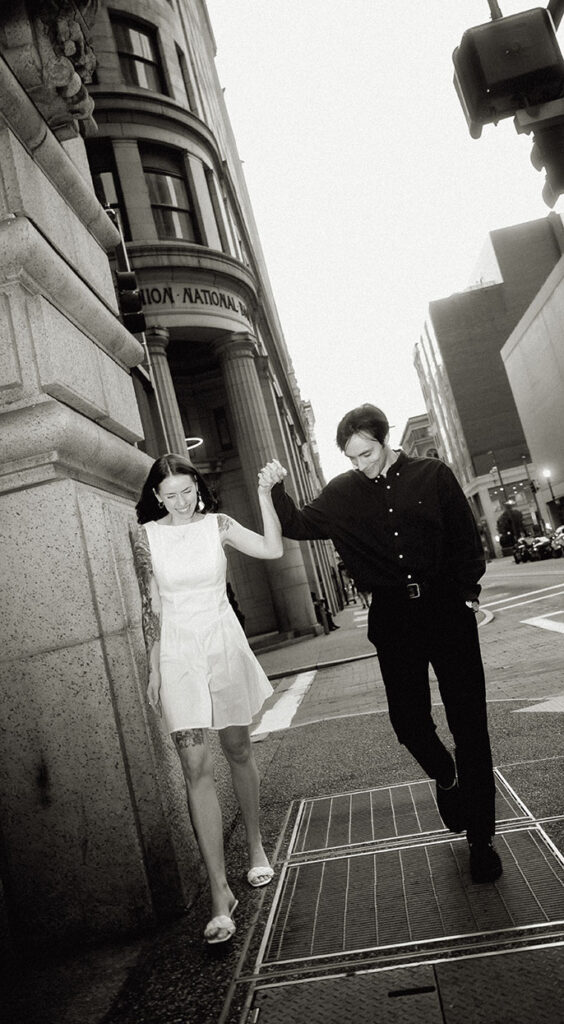 Couple walking hand in hand down Smithfield Street surrounded by nighttime city lights.
