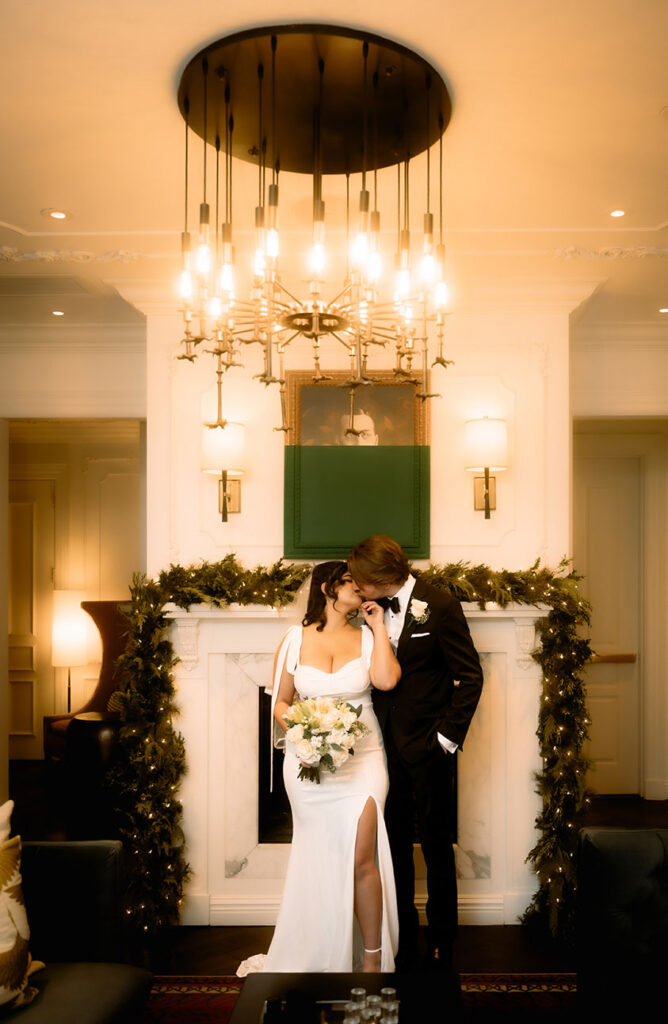 Bride and Groom Kiss in front of the chimney at the Kimpton Monaco Hotel with the Christmas Decorations.