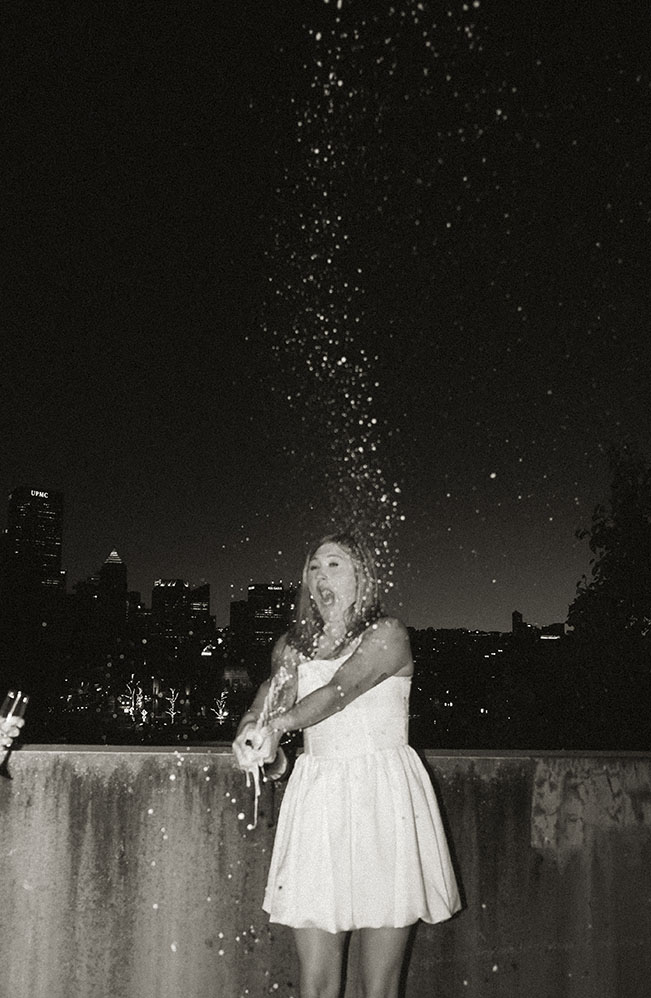 Cinematic rooftop champagne pop with Pittsburgh skyline lights during couple photoshoot