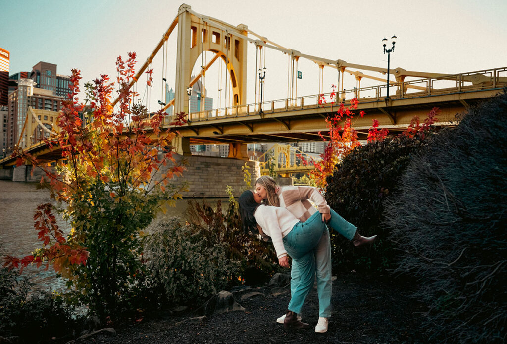 Cinematic couple photo on the Roberto Clemente Bridge with the Pittsburgh skyline at sunset.
