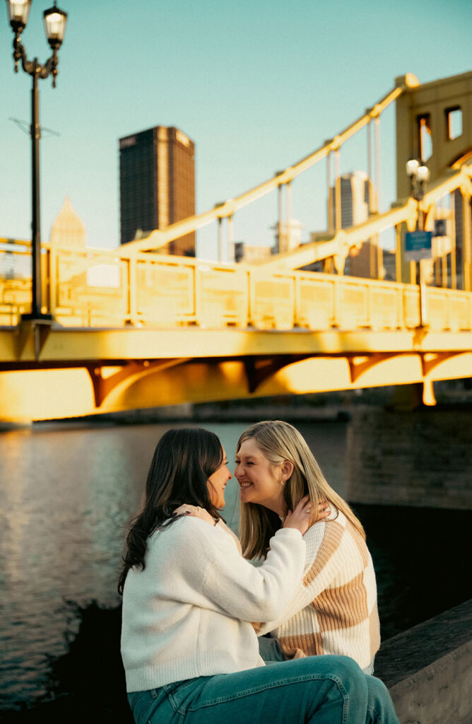 Romantic editorial photo of a couple kissing in front of the Pittsburgh skyline.