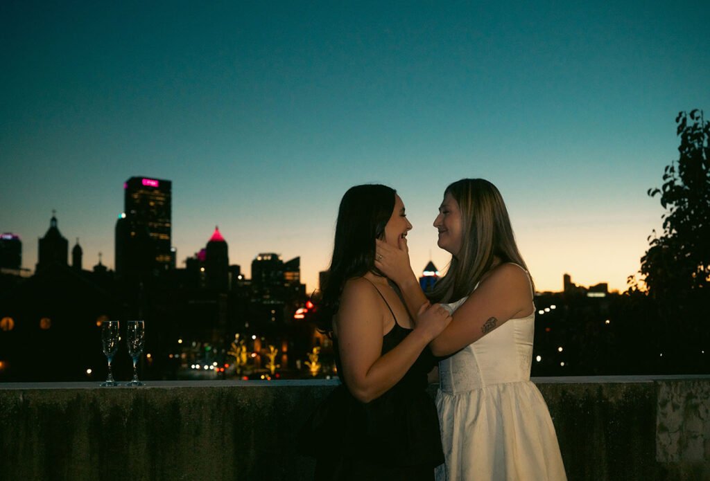 Cinematic rooftop champagne pop with Pittsburgh skyline lights during couple photoshoot