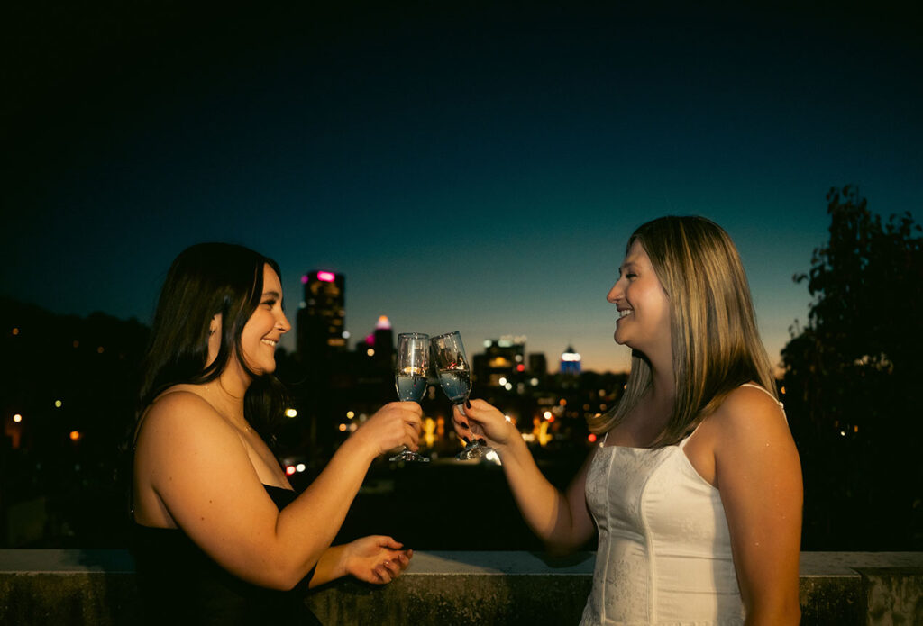 Cinematic rooftop champagne pop with Pittsburgh skyline lights during couple photoshoot