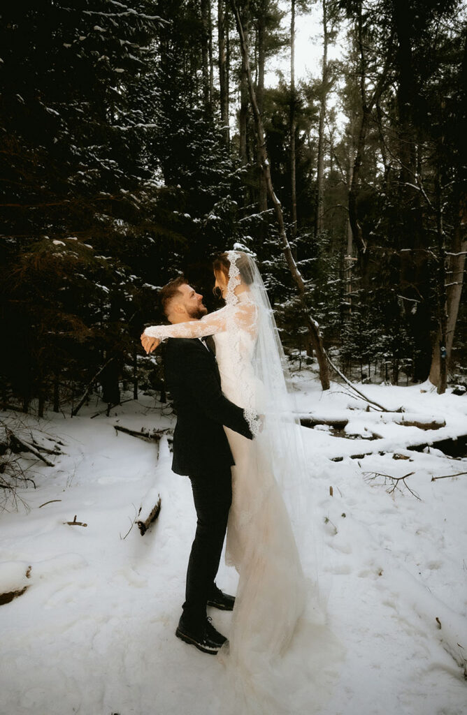 Bride and Groom looking at each other in the woods surrinded by snow and nature in the Pocono Mountains.