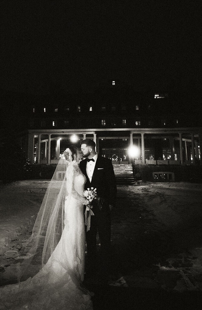 Bride and groom kissing outside Skytop Lodge at night under full moon