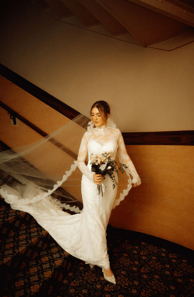 Bride in vintage lace wedding gown posing in softly lit Skytop Lodge hallway