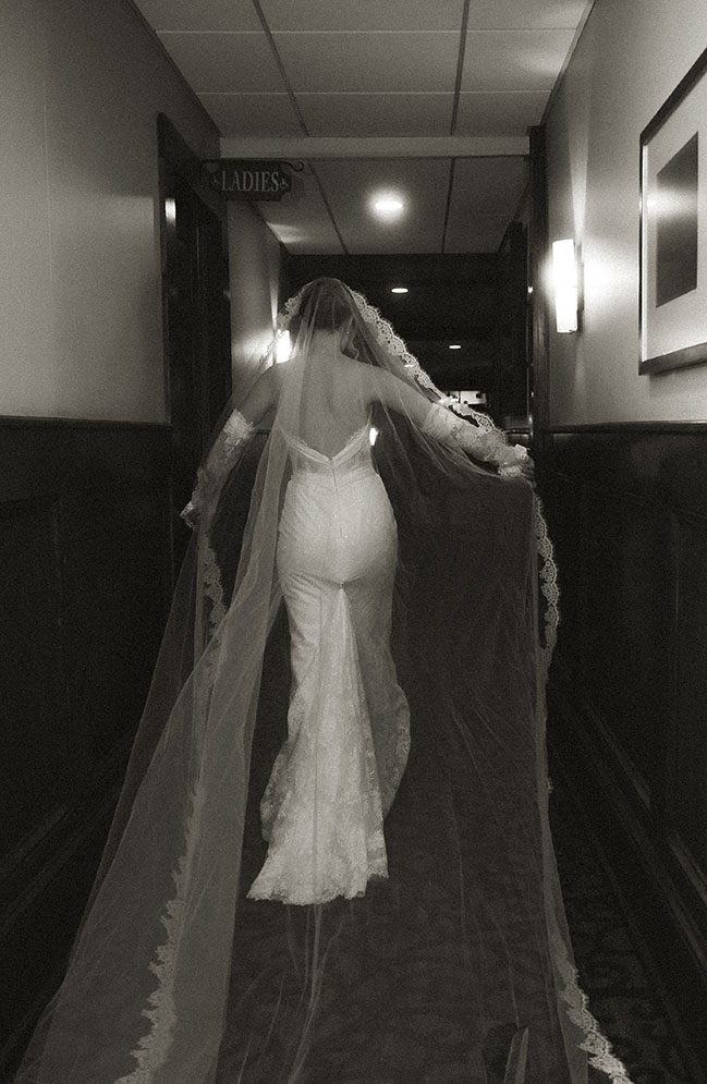 Bride walking away showcasing long lace veil highlighting vintage sleeves and lace textures