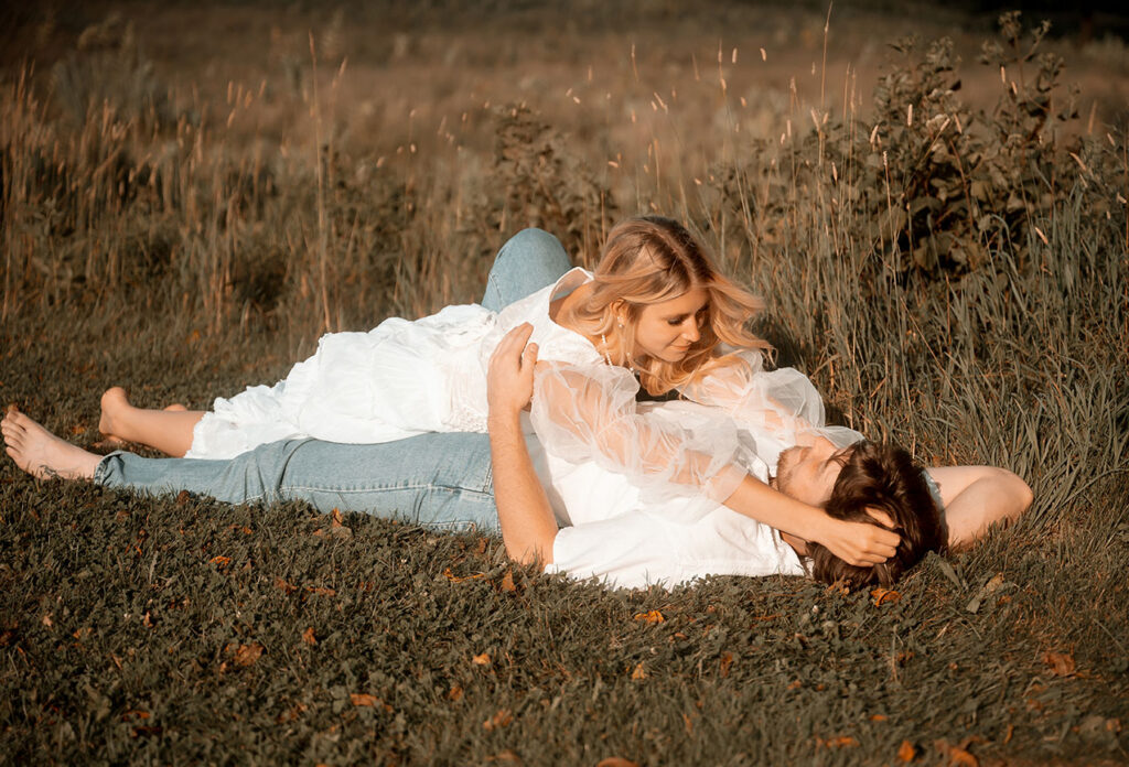 Intimate summer engagement photo in Pittsburgh park showing couple embracing on blanket