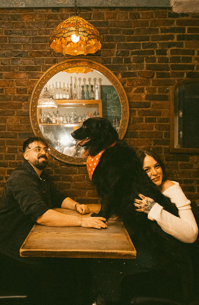 Playful engagement photo with couple and dog in Pittsburgh capturing relaxed and personal storytelling moment