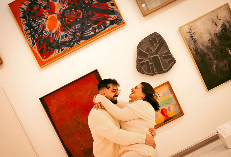 Editorial engagement photo inside Carnegie Museum of Art in Pittsburgh with couple standing near classical paintings and soft gallery light