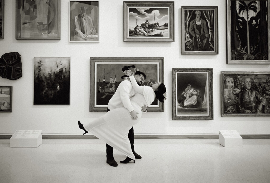BW Couple Dipping in front of paintings at Carnegie Museum of Art creating a timeless editorial engagement look in Pittsburgh