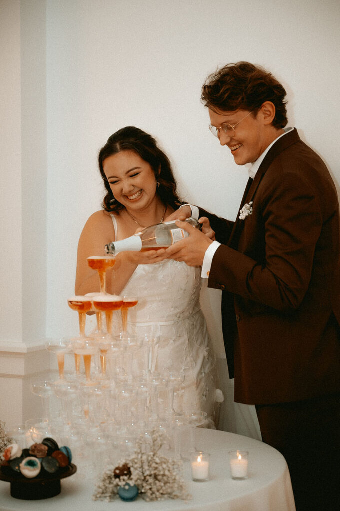 Bride and groom laugh pouring champagne at downtown pittsburgh wedding