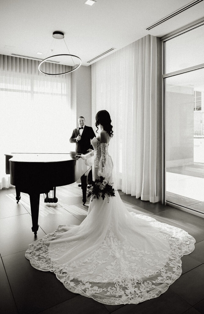 Bride wearing lace wedding gown in black and white portrait.
