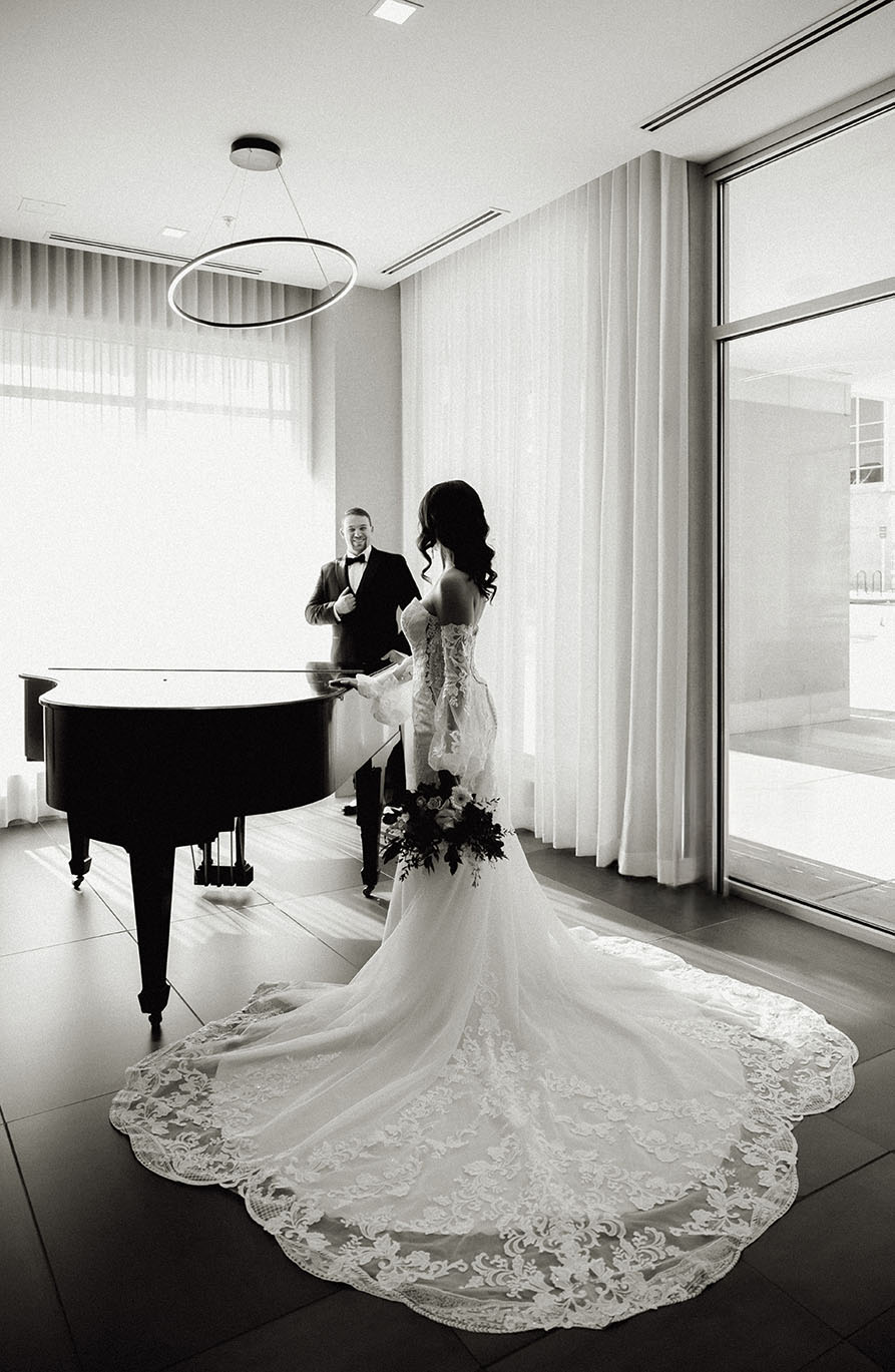 Bride wearing lace wedding gown in black and white portrait.