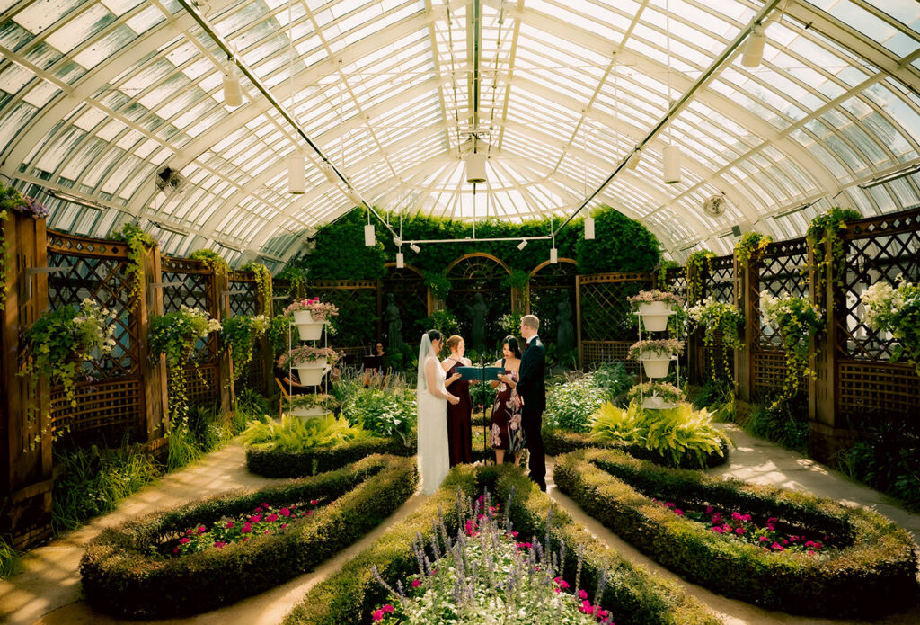 Wide view of an intimate wedding ceremony surrounded by formal gardens inside Phipps Conservatory.