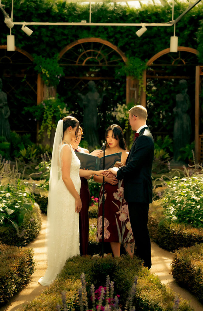 Wide view of an intimate wedding ceremony surrounded by formal gardens inside Phipps Conservatory.